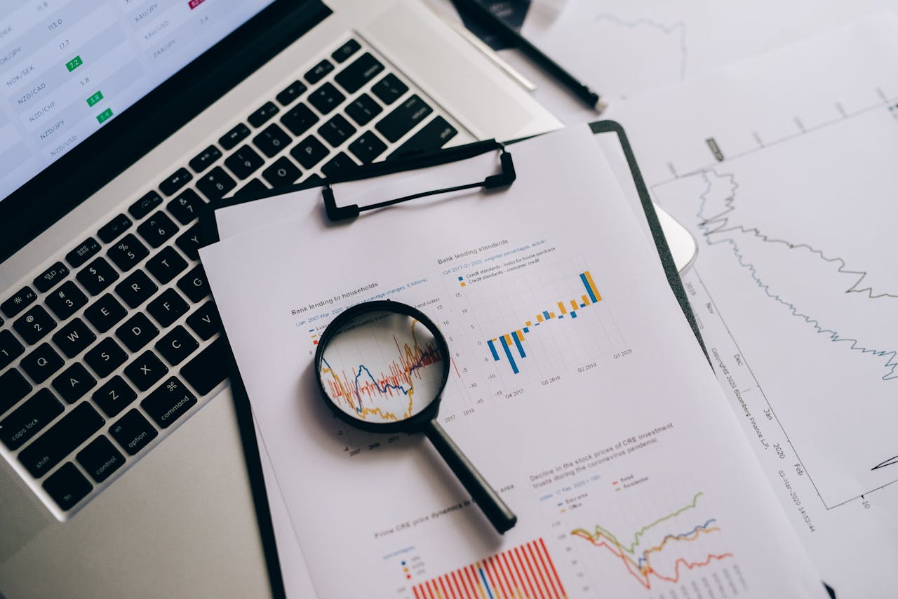 about-us-01 Overhead view of financial charts, laptop, and magnifying glass, ideal for business analysis themes.